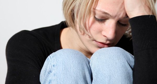 Woman sitting down holding her head looking worried